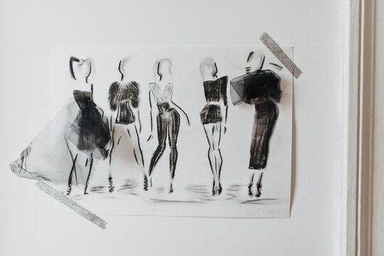 Photo of black clothing samples. Snaphot of painted girls in stylish dark outfits on white paper sheet