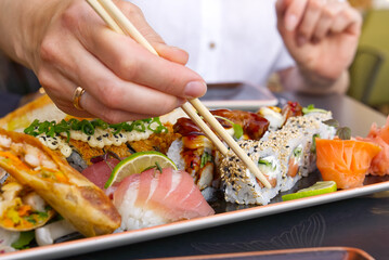 eating sushi with chopsticks at sushi restaurant woman holding sushi roll with wooden chopsticks