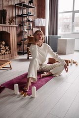 Pretty young calm female meditating relaxing sitting on natural mat in cozy home interior on weekend. Woman's wellness