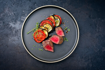 Modern style fried angus beef filet steak with traditional French ratatouille served as top view on...