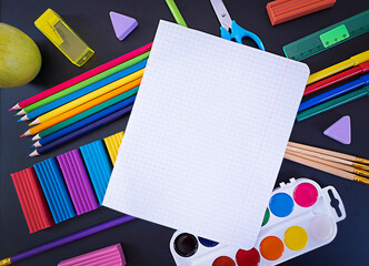 Concept back to school, school supplies on black chalkboard with an open notebook, top view with copy space