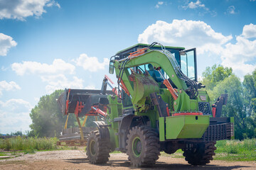 Fototapeta premium Construction equipment (tractor with a bucket) works in the park.