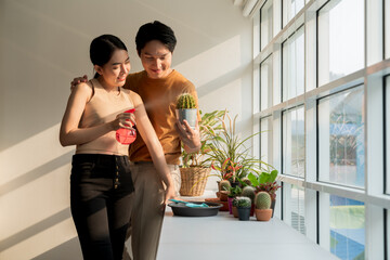 Happy Asian couples spend their free time taking care of and spraying water on the cactus plants by...