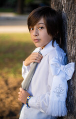 portrait of a boy adjusting his tie, dressed for his first communion.