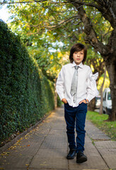 handsome boy walks along a sidewalk surrounded by trees