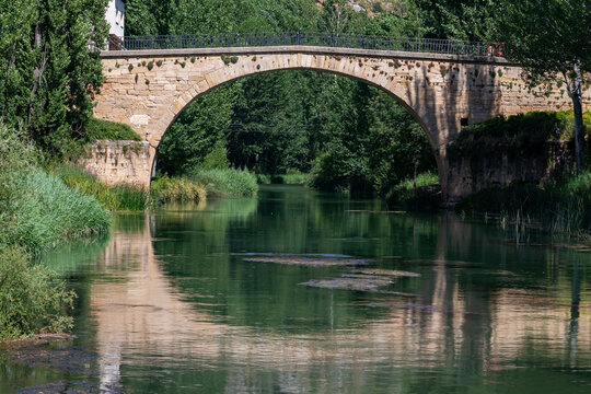 Rio Tajo as it passes through the town of Trillo in Guadalajara. Rio Grande. Urban landscape. Lush trees on the banks of the river Tagus. Medieval bridge over the river Tagus