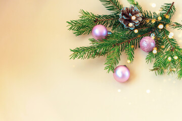 Christmas and New Year holiday background. Christmas tree branches, balls and pine cone on yellow background. Top view, flat lay, copy space