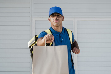 African american delivery man delivering fast food meal package in paper bag from cafeteria restaurant - Focus on face