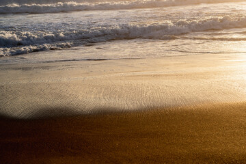 Isolated view of the waves on the shore at sunset.