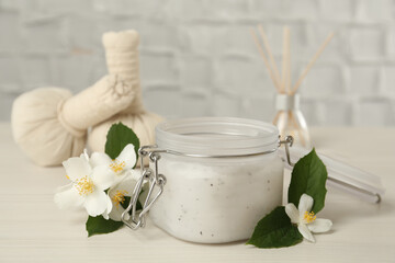Obraz na płótnie Canvas Jar of salt scrub and beautiful jasmine flowers on white wooden table