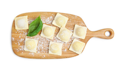 Wooden board with raw ravioli on white background, top view