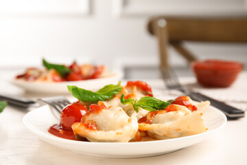 Tasty ravioli with tomato sauce served on white table