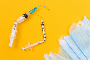 Anti Vaccine Movement and Anti Mask Concept - Broken Medical Syringe and Torn Medical Face Mask...