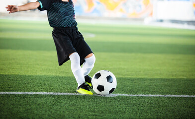 Selective focus to football with motion blur of kid soccer player shoot it on artificial turf....