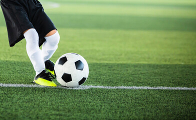 Selective focus to football with motion blur of kid soccer player shoot it on artificial turf....