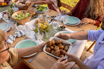 People Passing Tray of Baked Potatoes