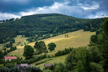 A mountain landscape, Kowadlo peak in Gory Zlote, Klodzka Valley, Poland. Golden cereal fields, green forest, cloudy sky, summer day.  © Kati Lenart