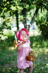 A happy child runs among the cherry trees. girl picks fresh cherry berry in garden during the harvest in summer.