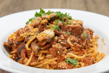 Large bowl of fettuccini bolognese pasta covered in sauce, mushroom, and garnishment for a hearty meal