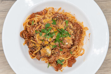 Overhead view of large bowl of fettuccini bolognese pasta covered in sauce, mushroom, and garnishment for a hearty meal