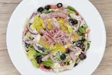Overhead view of huge bowl of antipasta salad with all fresh vegetables chopped and piled high and covered in cheese
