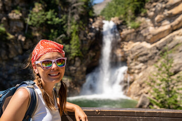 Cute woman hiker with braided hair wearing a tank top poses at Running Eagle Falls waterfall in...