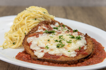 Delicious piece of parmesan chicken over marinara sauce with pasta on the side