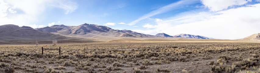 A panorama of distant mountain peaks with white clouds and blue skies in Idaho.