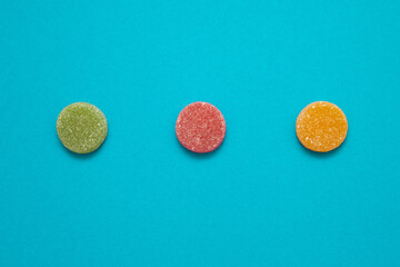 Colored round gummy candies isolated on blue background with copy space