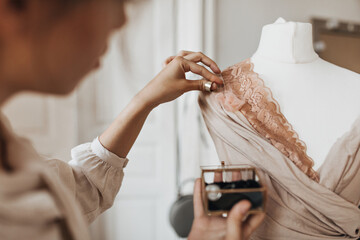 Stylish woman in beige outfit designed dress with lace. Young creative lady in blouse works on...