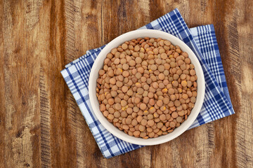 Walnut wood textureLentils in a Ceramic Bowl. These nutritious legumes are high in protein and fiber. The image is a cut out, isolated on a white background, with a clipping path.