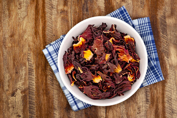 Dry Organic Jamaica Flower Hibiscus for Tea. Top view of bowl with Jamaica Flower Hibiscus. Detailed view of hibiscus tea on wooden background