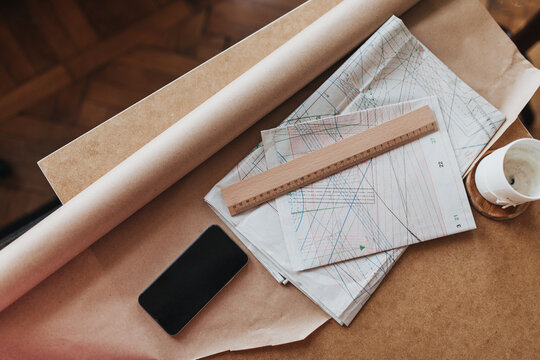 Snaphot of paper clothing patterns at table. Photo of craft sheets with painted stylish garments on them. Flatlay