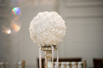 White round faux flower in glass cylinder vase with silver base centerpiece at wedding reception...
