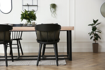 Stylish wooden dining table and chairs in room. Interior design