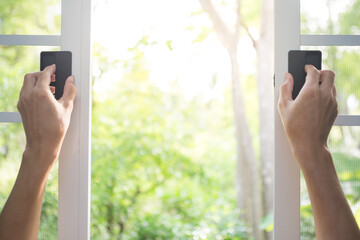 Hand holding open white window with natural blurred background  and sunlight