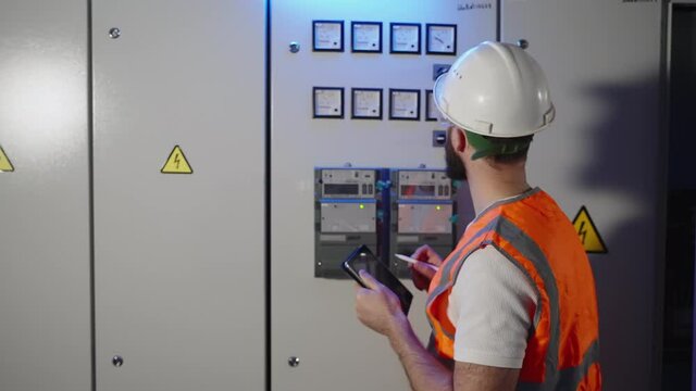 Electrician taking the readings of meter at the factory