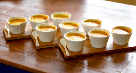 Creme brulee in white ramekins lined with white spoons on a rustic background