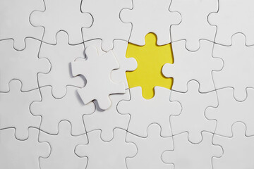 Unfinished white jigsaw puzzle pieces on yellow background