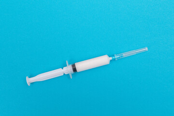 A Syringe with White Liquid Inside on Blue Table. Disposable Plastic Syringe is Prepared for...