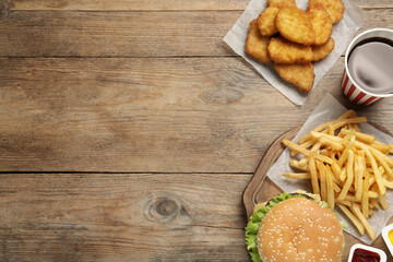 Flat lay composition with delicious fast food menu on wooden table. Space for text