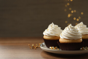 Delicious cupcakes decorated with cream on wooden table, space for text