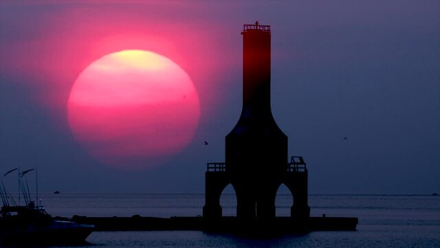 Eerie, otherworldly, red sunrise next to lighthouse. The extreme red is the product of ash in the atmosphere from fires in the Western US,  Climate Change.