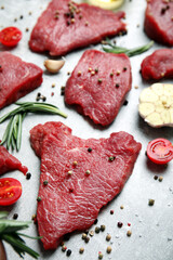 Fresh raw meat steaks and spices on light grey table
