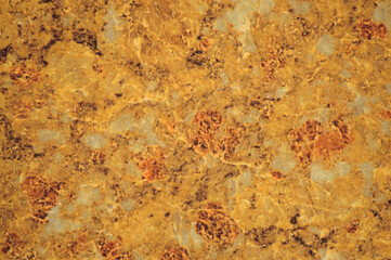 Golden marble with small inclusions of white and gray, close-up of polished Plao surface of natural stone.