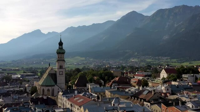 Aerial view of mountain town in Austria with churches,colorful houses, tower,  summer scenery at sunset,  Austrian Alps from above, Austria, Europe