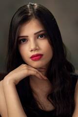 Fototapeta premium Fashion photo of a beautiful model with long hair, wearing black top, fashion pose, studio portrait, dark background, close up pic.