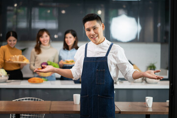 Young Asian Man Chef Wearing Apron with Two Women Preparing Food in the Kitchen.
