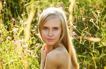 Beautiful young female with blond hair posing nude in nature, on a summer day.