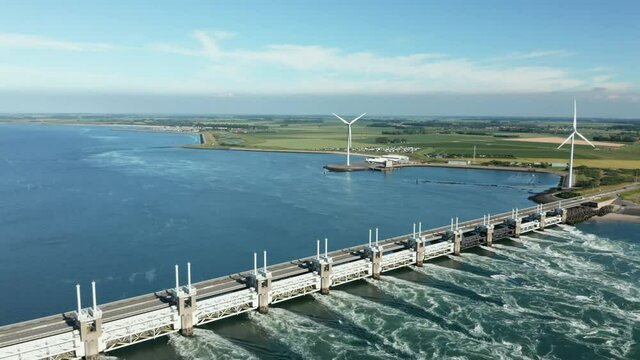 Oosterscheldekering Dam And Coastal Wind Turbines At Kamperland Village In Zeeland Province Of Netherlands. aerial
